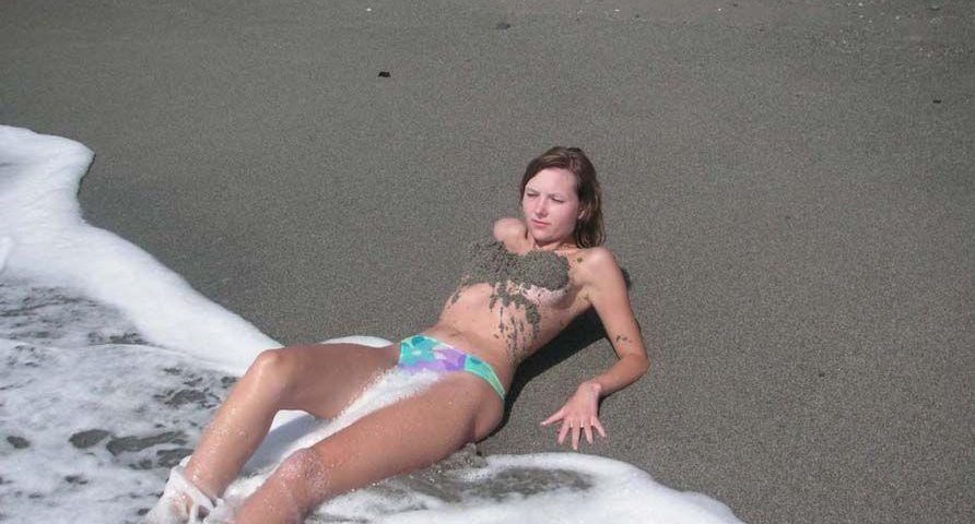 Seksi devojka na plaži sa peskom na grudima